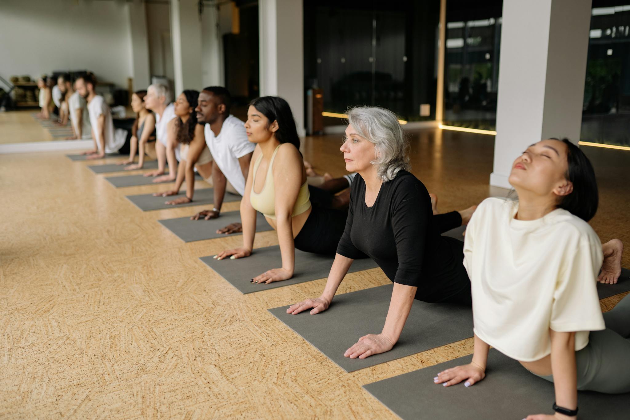 A diverse group of adults practice yoga indoors, demonstrating healthy lifestyles.